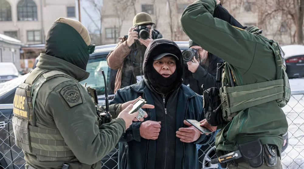 دورية من حرس الحدود الأميركي تفحص جواز سفر ووثائق أحد الأشخاص قبل اعتقاله في مينيابوليس بولاية مينيسوتا (أ.ف.ب)
