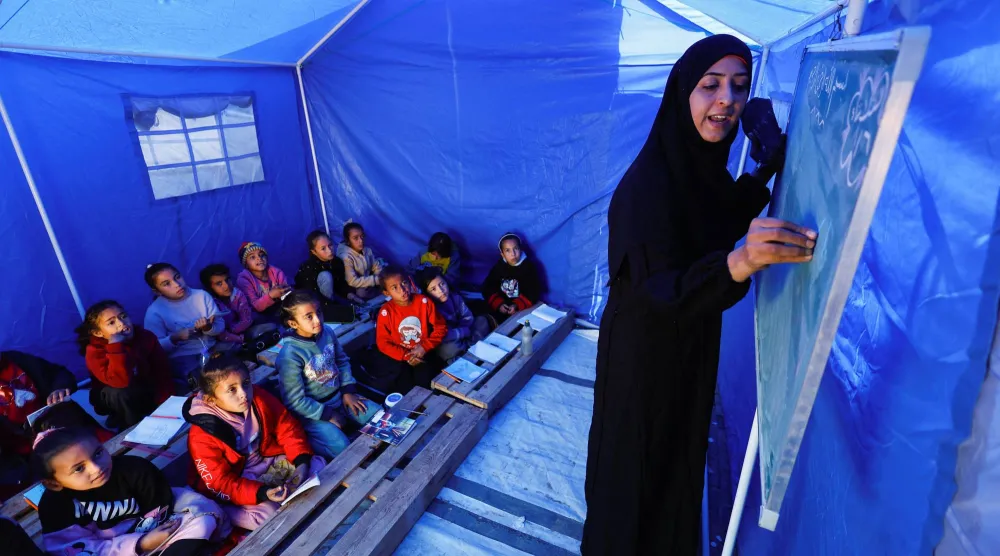 
أطفال فلسطينيون نازحون يتلقون الدروس داخل خيمة قرب الخط الفاصل بين «حماس» وإسرائيل في بيت لاهيا شمال غزة (رويترز)