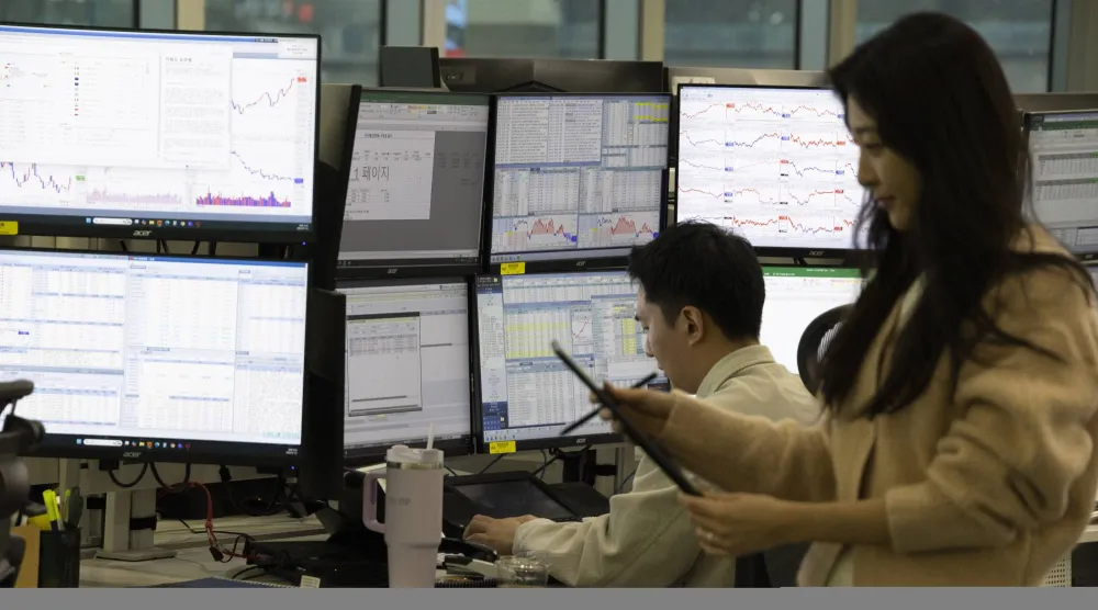 يعمل متداولون كوريون جنويون أمام شاشات عرض الأسهم في بنك هانا بسيول (إ.ب.أ)