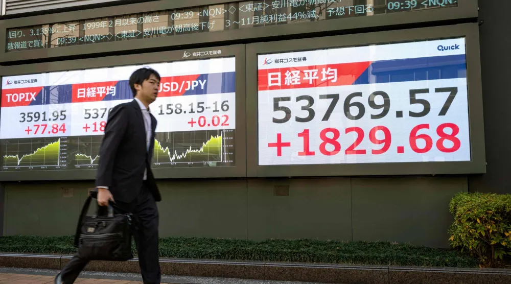 رجل يمر أمام شاشة إلكترونية تعرض حركة الأسهم في وسط العاصمة اليابانية طوكيو (أ.ف.ب)