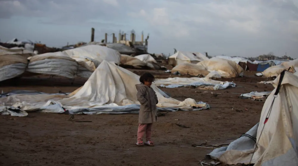 تقف فتاة فلسطينية بجوار خيام تضررت جراء الأمطار الغزيرة في الجزء الغربي من مخيم النصيرات للاجئين وسط قطاع غزة (د.ب.أ)