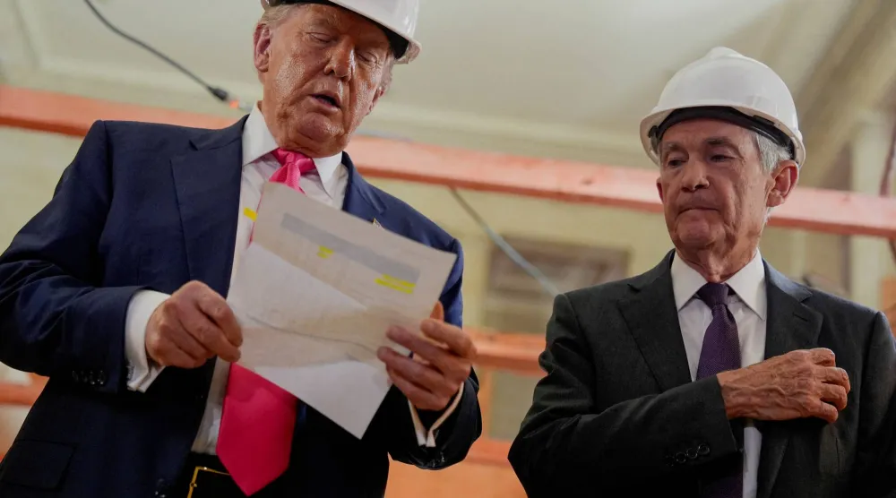 باول ينظر إلى ترمب وهو يحمل وثيقة خلال جولة للأخير بمبنى «الاحتياطي الفيدرالي» في يوليو (رويترز)