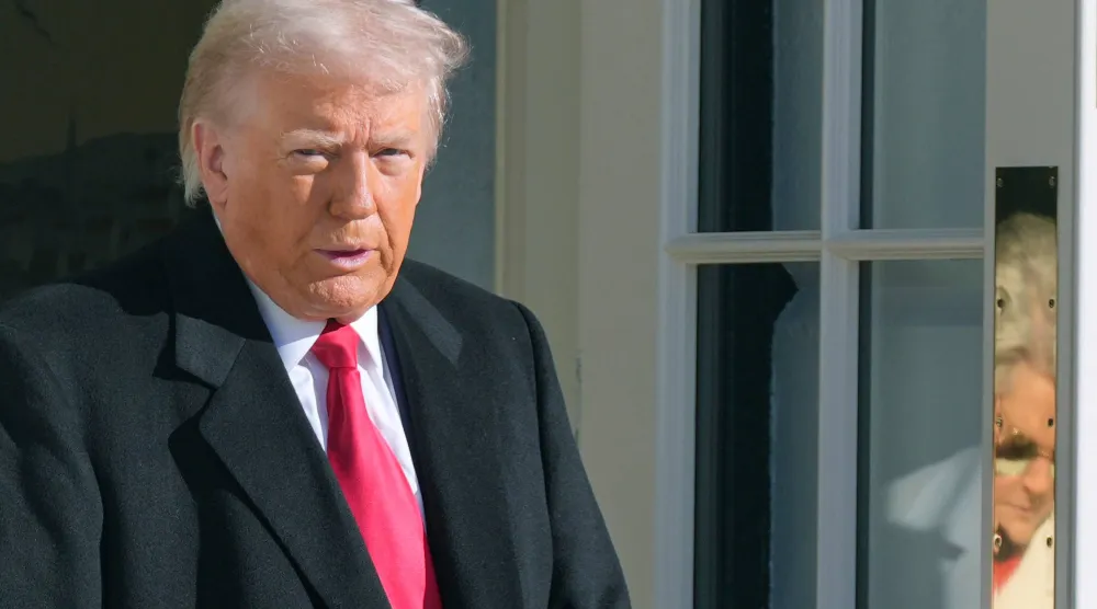  President Donald Trump and White House Chief of Staff Susie Wiles, reflected on door, leave to board Marine One, Tuesday, Jan. 13, 2026, in Washington. (AP) 