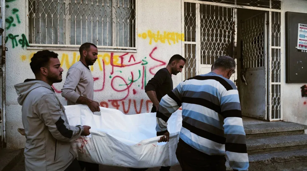 فلسطينيون يحملون جثمان طفلة قتلتها النيران الإسرائيلية في أثناء تشييعها من مستشفى الشفاء بمدينة غزة (أ.ب)