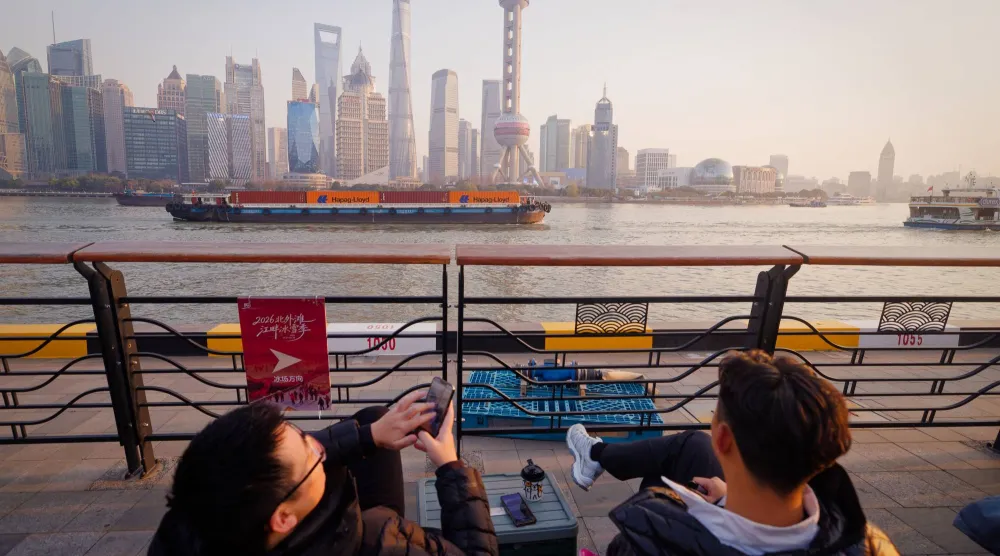 رواد مقهى يشاهدون سفن شحن تعبر نهر هوانغبو في شنغهاي (إ.ب.أ)