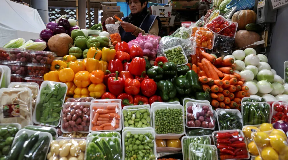 سيدة تقف أمام خضراوات في ميكسيكو سيتي (رويترز)