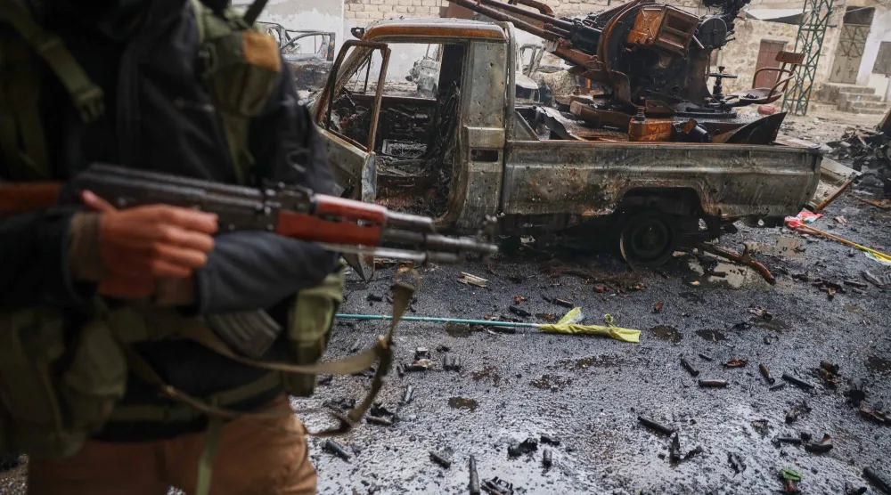أحد أفراد قوات الأمن السورية يقف بجوار مركبة مدمرة في حي الشيخ مقصود في مدينة حلب الشمالية بسوريا 12 يناير 2026 (أ.ب)