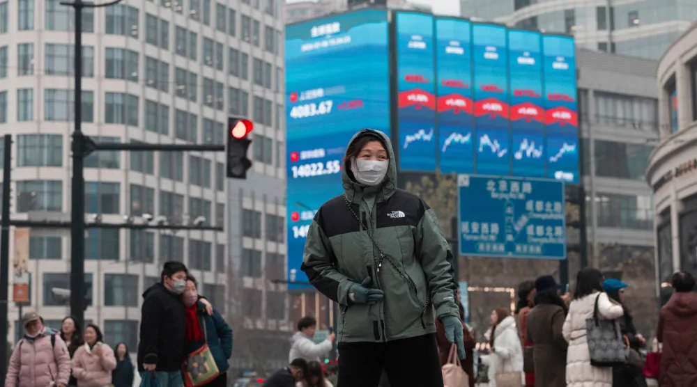 مشاة يمرون أمام شاشة عملاقة تعرض حركة الأسهم في مدينة شنغهاي الصينية (إ.ب.أ)