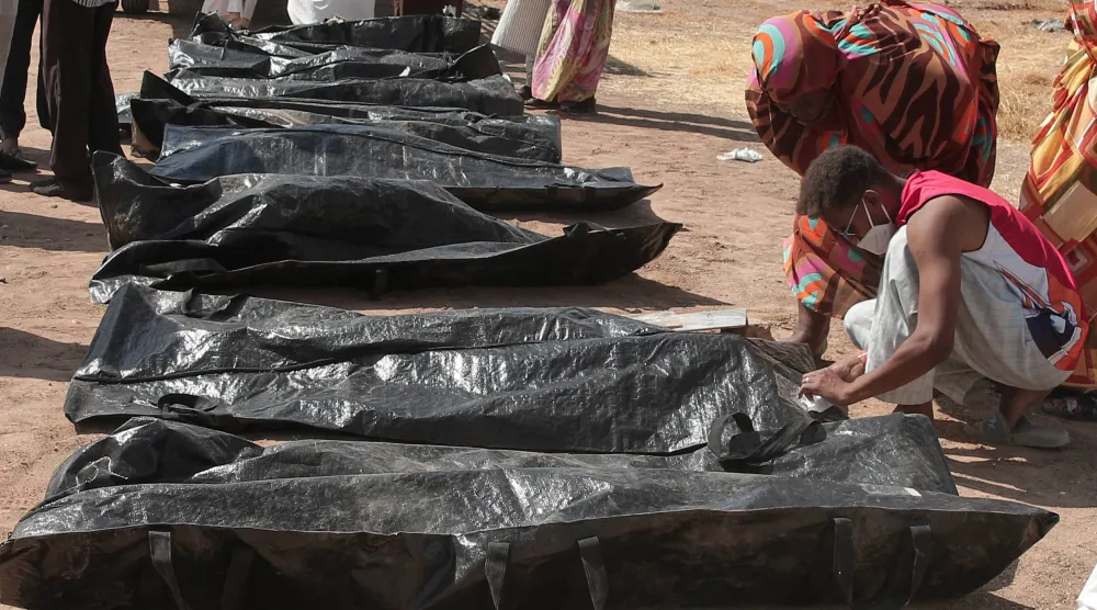 يتفقد أقارب ضحايا النزاع السوداني أسماءهم على أكياس الجثث بعد أن نقل الهلال الأحمر السوداني الرفات من مقابر مؤقتة إلى مقبرة محلية في الخرطوم (أ.ب)