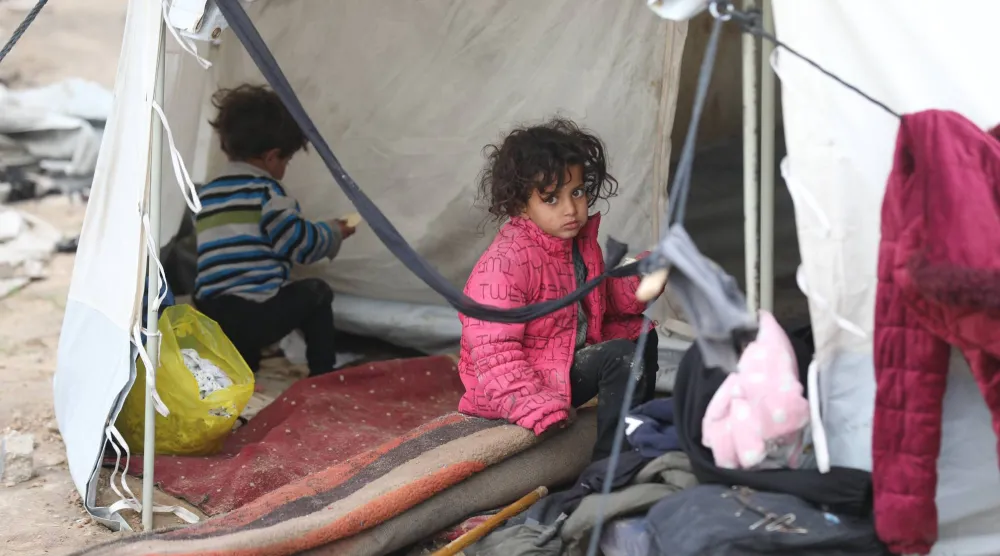 أطفال فلسطينيون يحتمون بخيام دمرتها الأمطار في مخيم النصيرات بقطاع غزة (د.ب.أ)