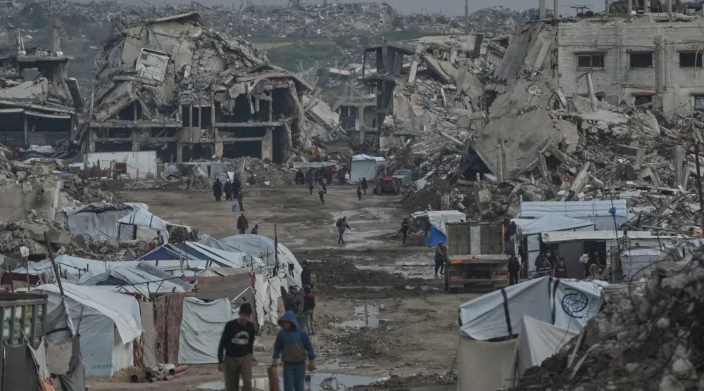 فلسطينيون يسيرون وسط مبانٍ دمرتها العمليات الجوية والبرية الإسرائيلية في حي الزيتون بمدينة غزة يوم 14 يناير 2026 (أ.ب) 