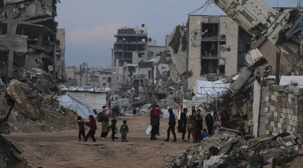 Filistinliler, Gazze Şeridi'ndeki Zeytun mahallesinde İsrail hava saldırılarıyla yıkılan binaların önünden geçiyor (AP)