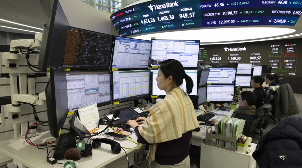 متداولون كوريون يعملون أمام شاشات تعرض مؤشرات الأسهم في بنك هانا بسيول (إ.ب.أ)