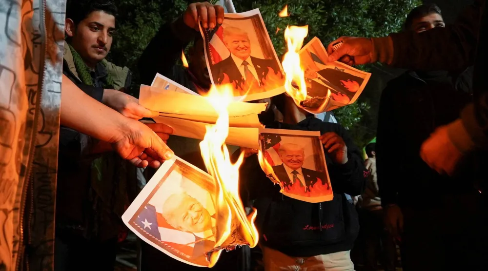 عراقيون يحرقون صوراً للرئيس الأميركي دونالد ترمب ورئيس الوزراء الإسرائيلي بنيامين نتنياهو خارج القنصلية الإيرانية بالبصرة 13 يناير 2026 (رويترز)