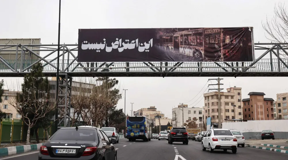 سيارات تسير في طهران تحت لافتة كتب عليها «هذا ليس احتجاجاً» الخميس (أ.ف.ب)