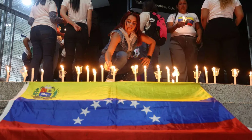 امرأة تضيء شمعة بجوار العلم الفنزويلي خلال وقفة احتجاجية للمطالبة بالإفراج عن السجناء السياسيين في فنزويلا يوم 13 يناير (أ.ف.ب)