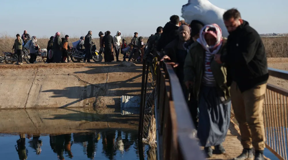 نازحون سوريون يسيرون لعبور معبر نهري بالقرب من قرية جريرة الإمام في ريف حلب الشرقي بالقرب من خط المواجهة بين القوات الحكومية و«قوات سوريا الديمقراطية» التي يقودها الأكراد في دير حافر 15 يناير 2026 (أ.ب)