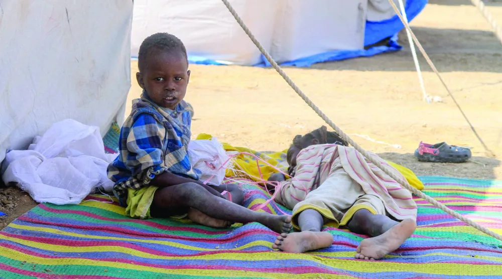 طفلان من الفاشر يستريحان في مخيم للنازحين السودانيين ببلدة الدبة الشمالية (أ.ف.ب)