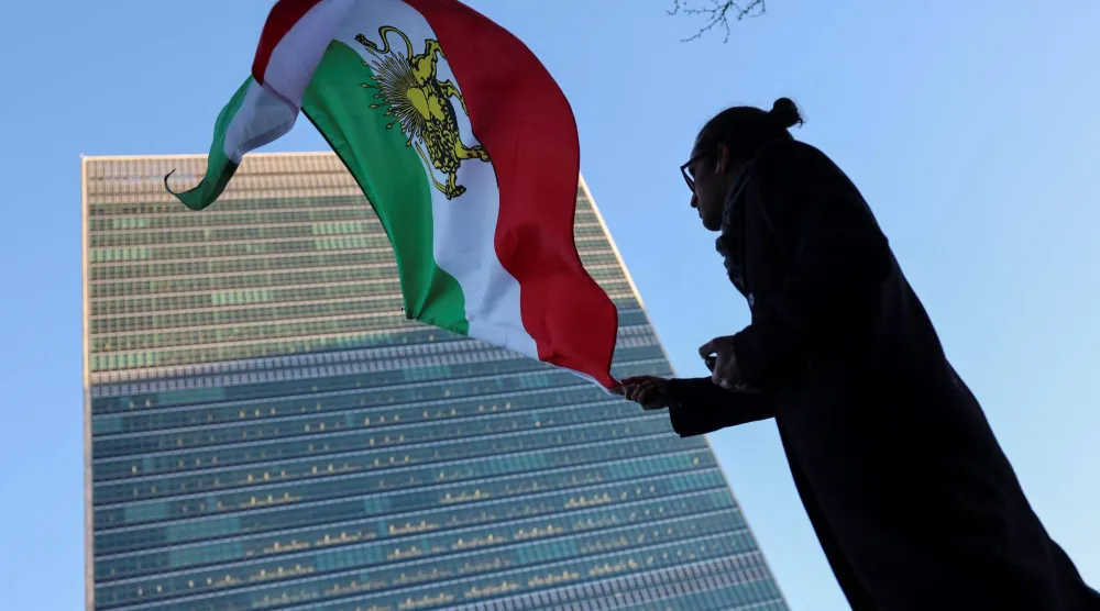 متظاهر يلوح بالعلم الإيراني وقت حكم الشاه خارج مقر الأمم المتحدة خلال اجتماع لمجلس الأمن الدولي حول إيران في نيويورك (أ.ف.ب)