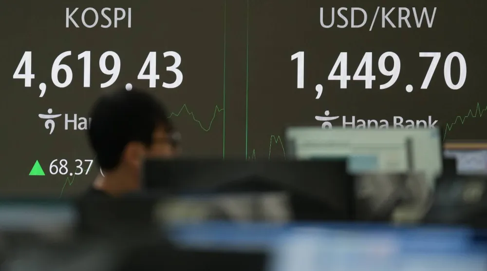 يمرّ أحد المتعاملين بجانب شاشات تعرض مؤشر «كوسبي» وسعر صرف الدولار الأميركي مقابل الوون في غرفة التداول ببنك هانا في سيول (أ.ب)