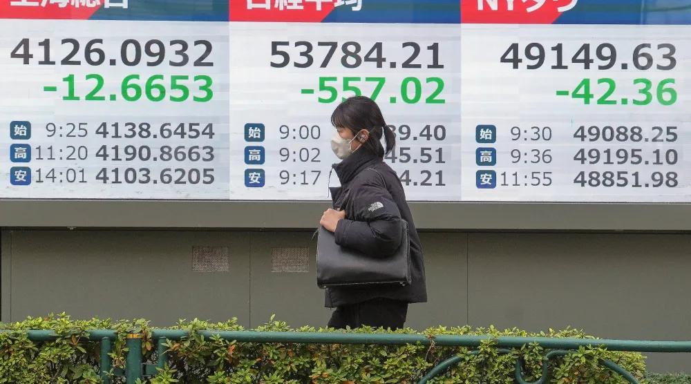 سيدة تمر أمام شاشة إلكترونية تعرض حركة الأسهم في وسط العاصمة اليابانية طوكيو (أ.ب)