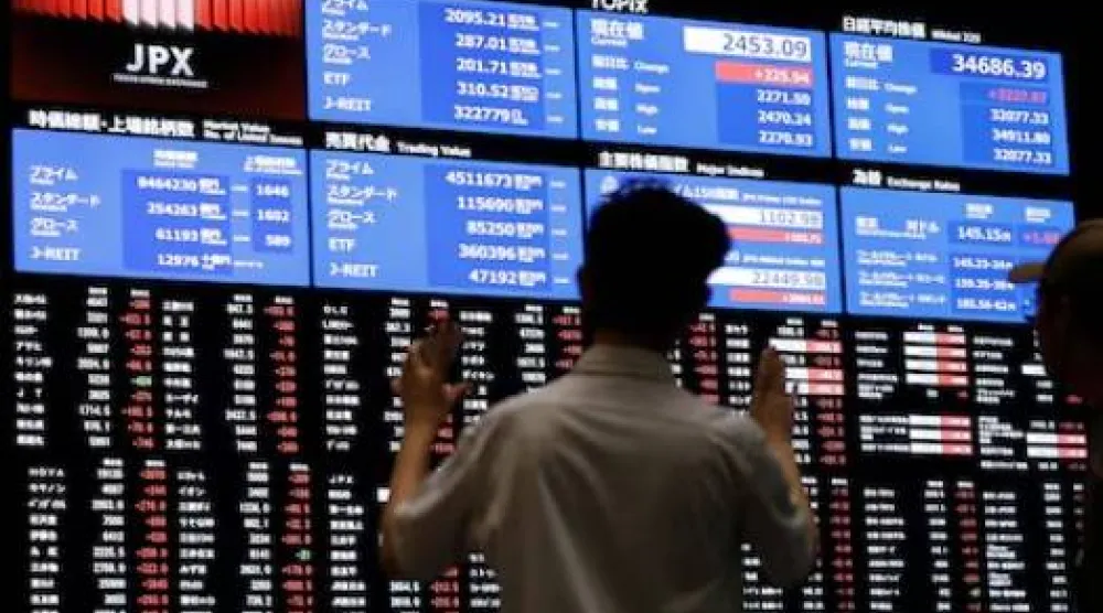 شخص يراقب لوحة أسعار الأسهم في بورصة طوكيو (رويترز)