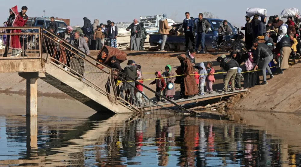 Sivil halk, Halep'in doğusunda SDG güçlerinin kontrolündeki bölgeden kaçarken hasarlı bir köprüyü geçiyor (AFP)
