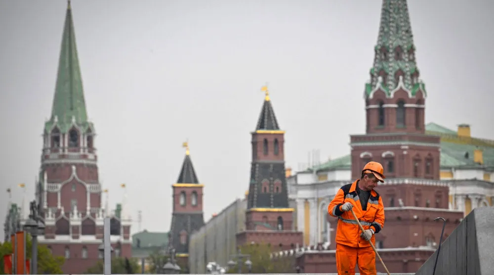 عامل نظافة في أحد الشوارع أمام الكرملين بالعاصمة الروسية موسكو (أ.ف.ب)