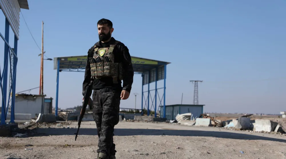 جندي مسلح يظهر بينما يغادر مدنيون من دير حافر باتجاه الغرب خوفاً من تصعيد التوتر بين قوات سوريا الديمقراطية والحكومة السورية (رويترز)