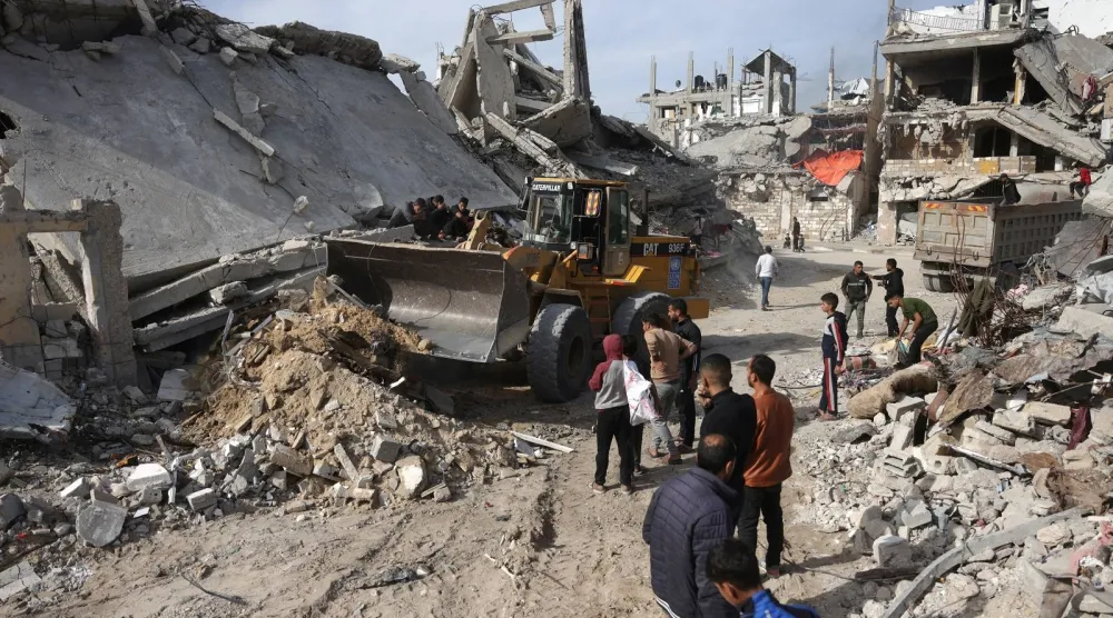 فلسطيني يقود حفاراً يُستخدَم لنقل الخرسانة والمعادن وحطام المباني والمنازل المُدمَّرة في خان يونس جنوب قطاع غزة (أ.ف.ب)