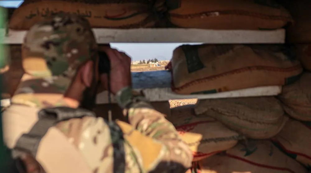 A member of the Syrian army monitors the frontline from a fortified military post in the Deir Hafer area, eastern Aleppo countryside, northern Syria, 16 January 2026. (EPA)