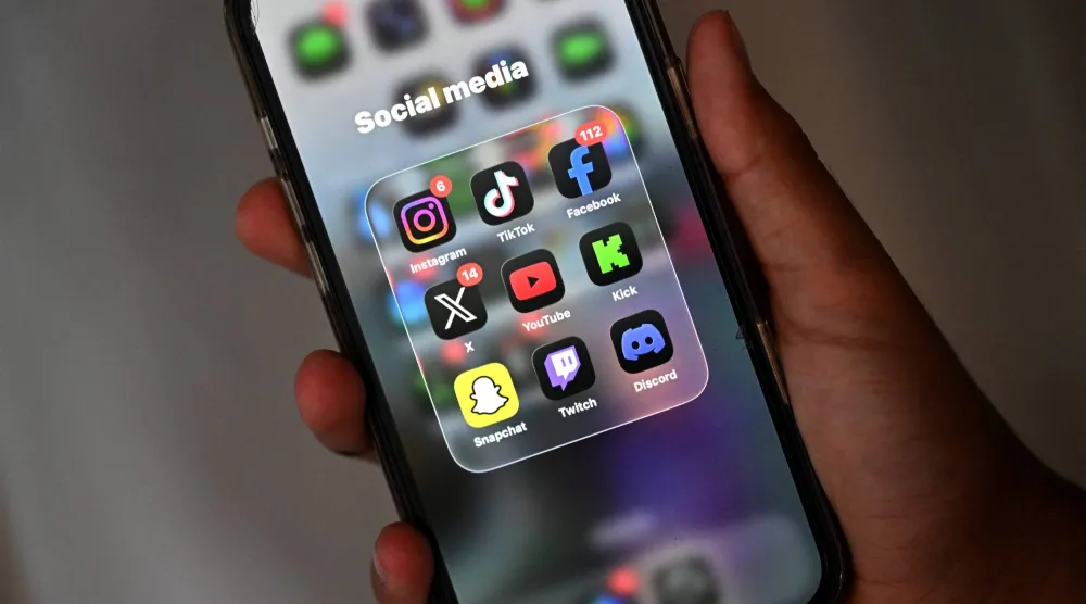 A 13-year-old boy poses at his home as he looks at social media on his mobile phone in Sydney on December 8, 2025.  (Photo by Saeed KHAN / AFP)