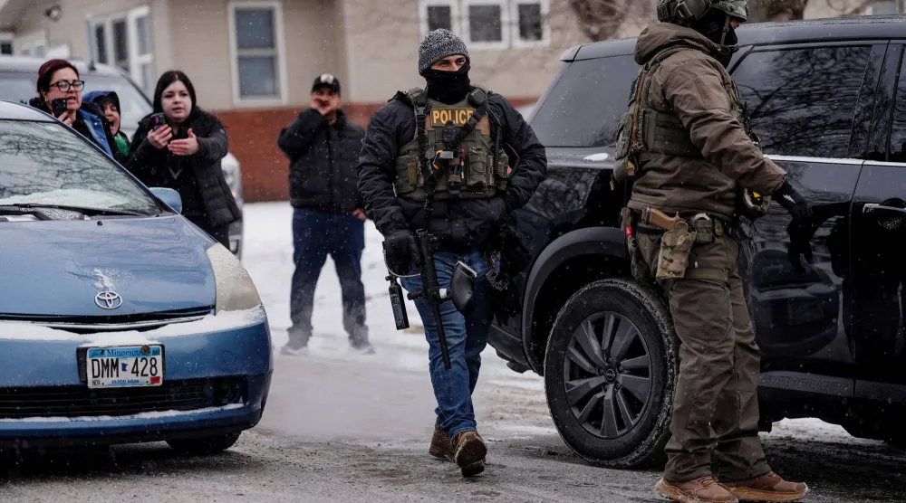 عناصر من هيئة الهجرة والجمارك الأميركية وضباط شرطة خلال تنفيذ غارات للبحث عن مهاجرين في ولاية مينيسوتا (رويترز) 