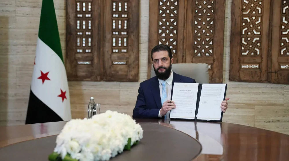 الرئيس السوري أحمد الشرع يرفع أمام الصحافيين اتفاقية وقف إطلاق النار والاندماج الكامل لـ«قسد» ضمن مؤسسات الدولة (أ.ف.ب)
