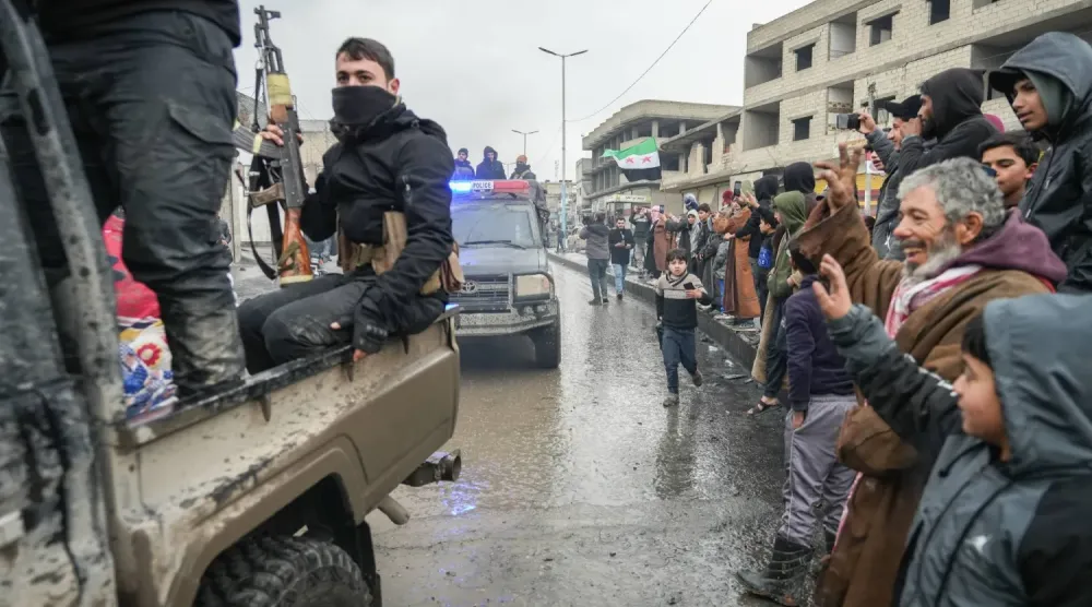 Yol kenarında sıralanarak, Rakka’daki Tabka ilçesine giren Suriye güvenlik güçlerine el sallayan Suriyeliler (EPA)