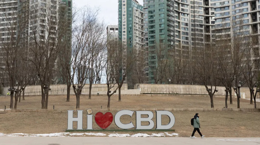 شخص يمر بجوار لافتة في الحي التجاري المركزي ببكين (إ.ب.أ)