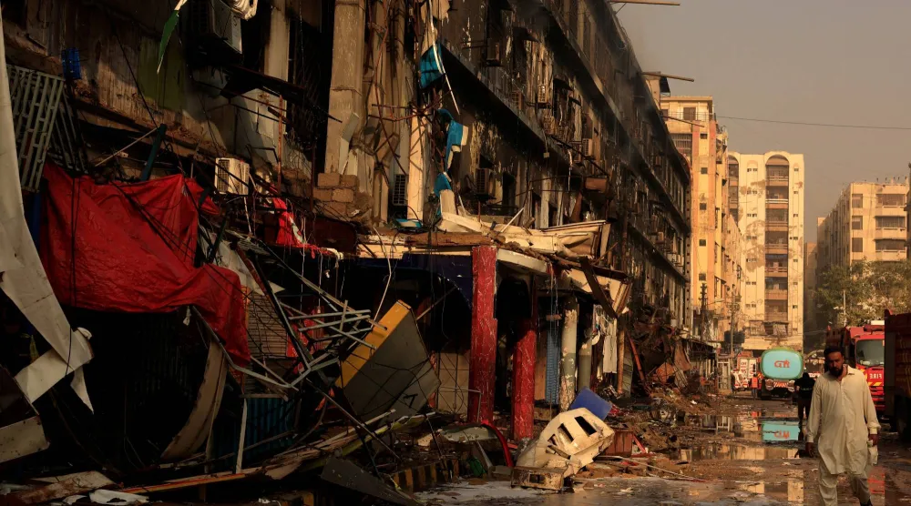 رجل يتجاوز الأنقاض عقب حريق هائل اندلع في مركز جول بلازا التجاري في كراتشي (رويترز)