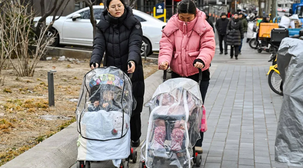  Women push baby strollers as they walk along a street in Beijing on January 4, 2026. (AFP)