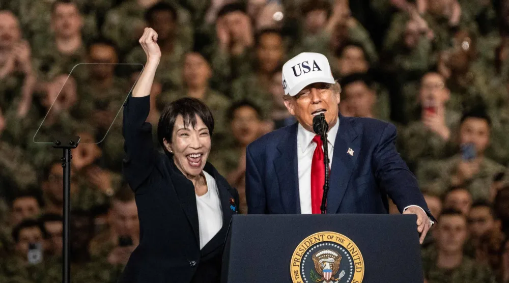 رئيسة الوزراء اليابانية ساناي تاكايتشي بجوار الرئيس الأميركي دونالد ترمب تحيي الجنود على متن حاملة طائرات في بحر اليابان العام الماضي (أ.ف.ب)