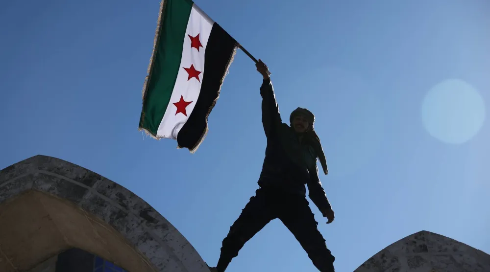جندي سوري يرفع علم بلاده في ميدان النعيم بالرقة بعد انتزاع السيطرة عليها من «قسد» (أ.ب)