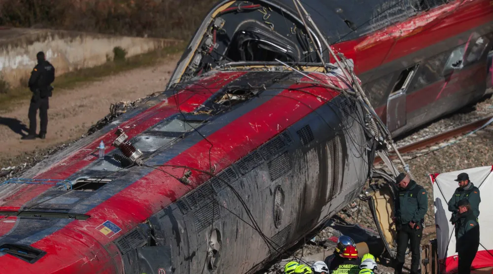 يعمل أفراد من الحرس المدني الإسباني إلى جانب فرق الإنقاذ الأخرى بجوار أحد القطارات المتورطة في الحادث في موقع خروج قطارين فائقَي السرعة عن مسارهما بالقرب من أداموز في إسبانيا (رويترز)