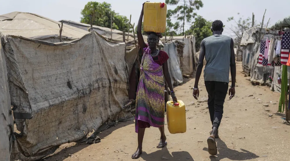 نازحة تحمل الماء على رأسها في مخيم جوبا للنازحين جنوب السودان (أ.ب)