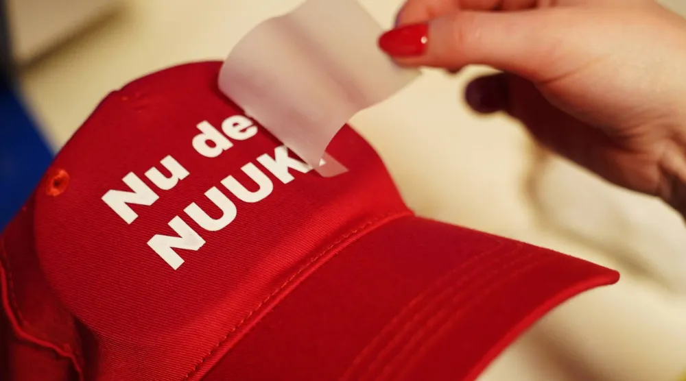 عاملة تحمل قبعة حمراء تحمل عبارة «الآن يكفي» باللغة الدنماركية في متجر في كوبنهاغن (أ.ب)