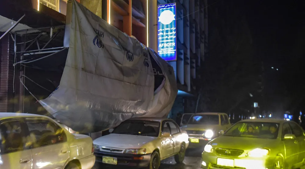 سيارات تمر إلى جاني المبنى الذي استهدفه التفجير في كابل (أ.ف.ب)