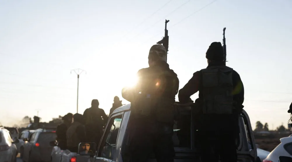 Syrian government forces brandish their weapons as they take possession of the SDF military base as they enter the city of Raqqa on January 19, 2026. (AFP)