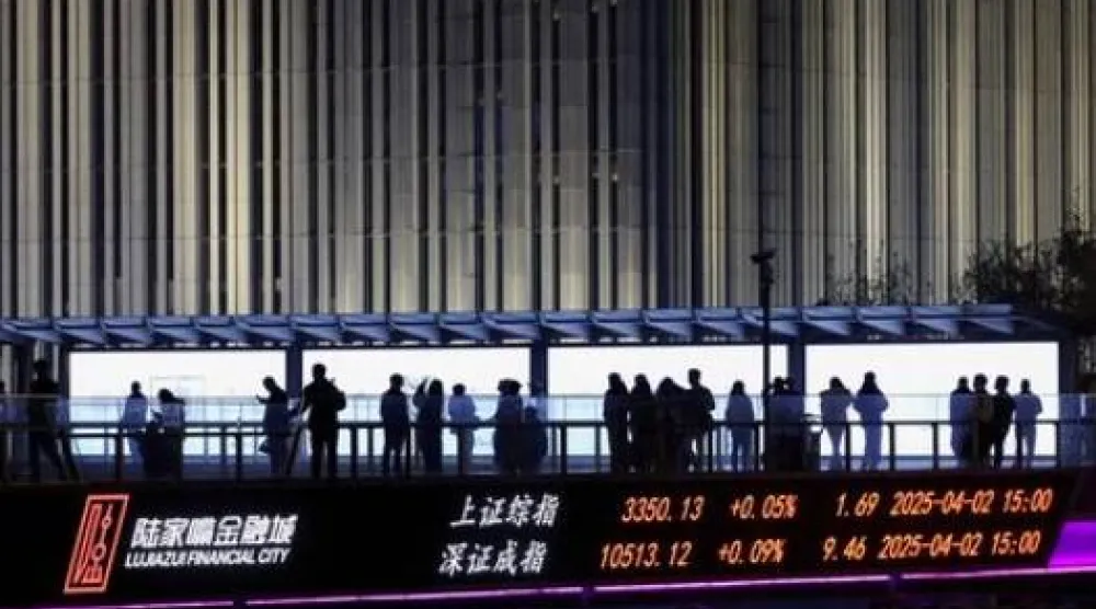 لوحة إلكترونية تعرض مؤشرات بورصتي شنغهاي وشنتشن بينما يمشي أشخاص على جسر للمشاة في منطقة لوجيازو المالية في شنغهاي (رويترز)