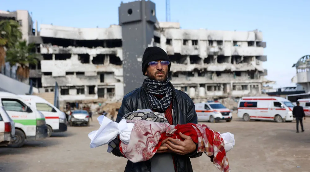 فلسطيني يحمل جثمان رضيعته البالغة 3 أشهر يوم الثلاثاء بعد وفاتها جراء البرد في مدينة غزة (أ.ف.ب)