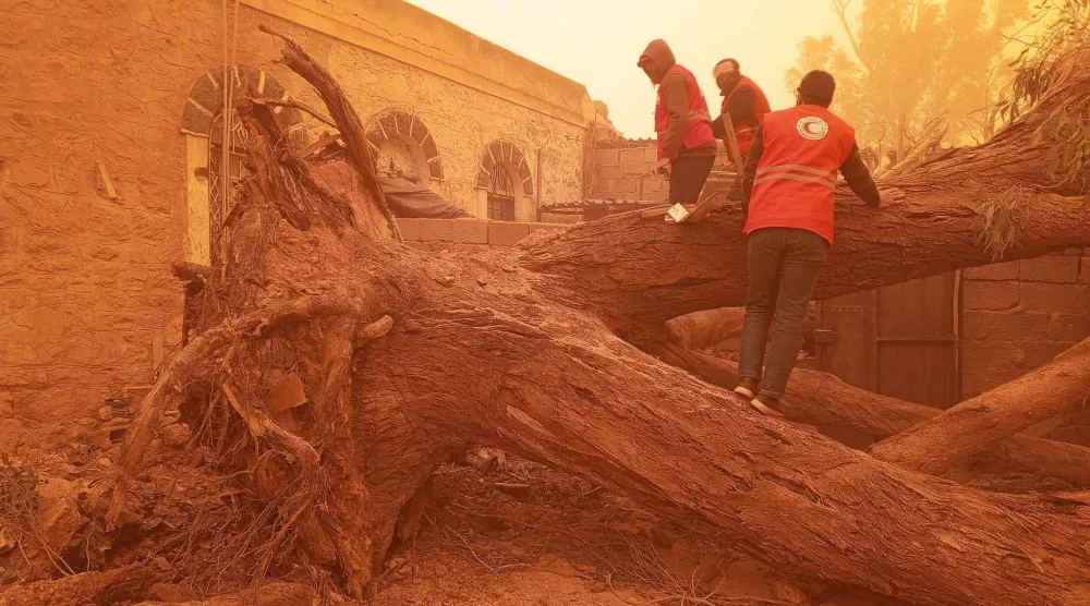 متطوعو «الهلال الأحمر» الليبي يجلون عائلة بعد تساقط الأشجار على منزلها (الهلال الأحمر)