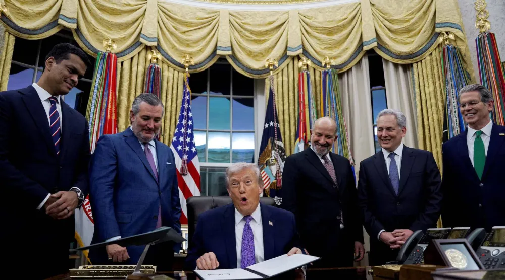 الرئيس الأميركي دونالد ترمب يحمل أمراً تنفيذياً وقّعه وتحيط به شخصيات من إدارته في المكتب البيضاوي بالبيت الأبيض في العاصمة واشنطن 11 ديسمبر 2025 (رويترز)
