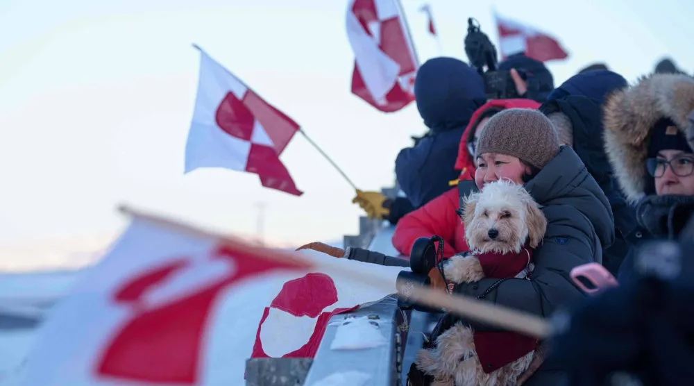 أشخاص يلوحون بالأعلام الوطنية ترحيباً بوزيرة خارجية غرينلاند فيفيان موتزفيلدت لدى وصولها إلى مطار نوك (أ.ب)